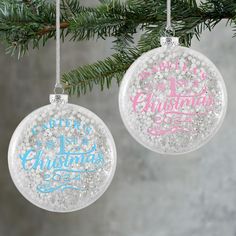 two ornaments hanging from a christmas tree decorated with glitter and the words merry christmas written on them