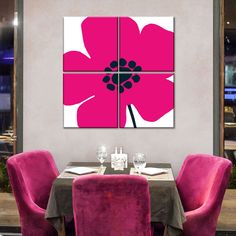 a dining room table with pink chairs and a large flower on the wall above it