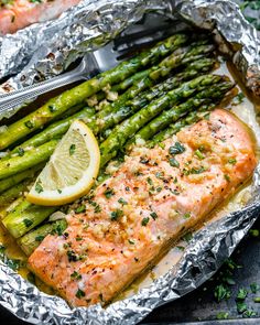 salmon and asparagus in foil with lemon wedges on the side for garnish