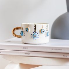 two coffee mugs sitting on top of a white table next to a gray lamp