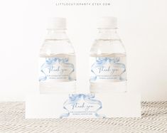 two bottled water bottles sitting next to each other on top of a white tablecloth