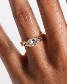 a woman's hand with a diamond ring on top of her finger, showing the center stone