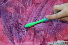 a person is painting with purple and green paint