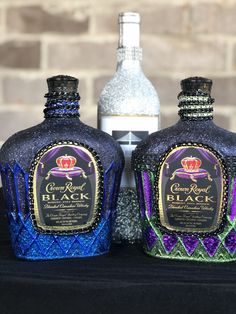 two bottles of crown royal black are sitting next to each other on a table in front of a brick wall