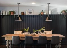 a dining room table and chairs with plants on the wall