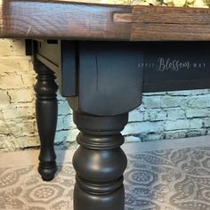 a black table with flowers on it in front of a brick wall and carpeted floor