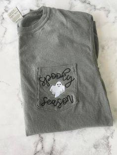 Perfectly soft every day t-shirt to wear!  Features the Spooky Season design on our super soft Comfort Colors T-shirt!   This is for our SHORT sleeve shirt only!  Comfort colors brand, Adult Unisex sizes 100% Cotton  Pocket will be sewn shut. When will this ship? How do the sizes run? Check the FAQs - https://www.etsy.com/shop/OurLilBowtique/policy *If you have an idea for a shirt and do not see it, please message me with your request so that I may create a custom listing for you. Let's make your dream shirt a reality! Thank you for choosing Our Lil' Bowtique. Halloween Cotton T-shirt With Text Print, Halloween Cotton Tops With Text Print, Halloween Cotton Top With Text Print, Gray Text Print T-shirt For Fall, Halloween Cotton T-shirt With Letter Print, Halloween Letter Print Cotton T-shirt, Gray Crew Neck T-shirt For Fall, Halloween Crew Neck Soft-washed T-shirt, Gray Cotton Top For Halloween