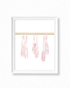 pink ballet shoes hanging from a line on a wooden stick in front of a white wall