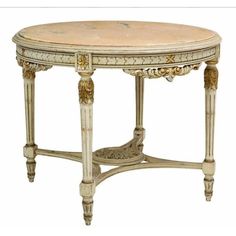 an ornate table with marble top and gold trimmings on the legs, is shown