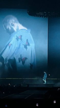 a man standing on top of a stage in front of a large screen