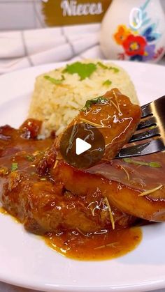 a white plate topped with meat covered in sauce and gravy next to rice