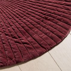 a large red rug on top of a wooden floor next to a white tile floor