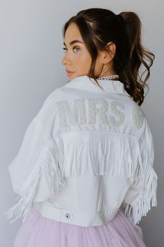 The Dallas Fringe is a cropped style white denim jacket with fringe tassels. Nice and light-weight - super comfortable. *Pearl Patch and Varsity Patches sold seperately* SIZE INFO Cropped fit S=0-4, M=6-10, L=12-14. DETAILS & CARE Front button closure Spread collar Chest button-flap pockets 100% cotton Hand wash/Spot Clean only to avoid patches coming off. Imported FINAL SALE Trendy White Cropped Denim Jacket, Trendy White Denim Jacket With Frayed Hem, White Tasseled Outerwear For Spring, White Spring Outerwear With Tassels, White Cropped Denim Jacket, Mrs Jean Jacket, Fringe Dress Outfit, Denim Jacket With Fringe, Fringe Wedding Dress