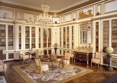 the room has many bookshelves and chairs in it, along with a chandelier