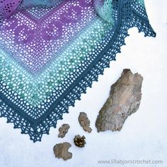 there is a crocheted blanket and some rocks on the ground