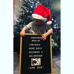 a little boy in a santa hat holding a sign