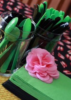 green and pink utensils in glass vases with napkins on the table