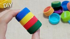 a person holding a stack of colorful plastic cups in front of some other colored objects