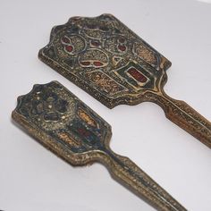 two antique looking metal spoons sitting next to each other on a white counter top