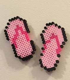 two pink and black beaded earrings on a white surface