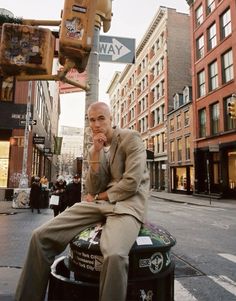 a man sitting on top of a suitcase talking on a cell phone next to a traffic light