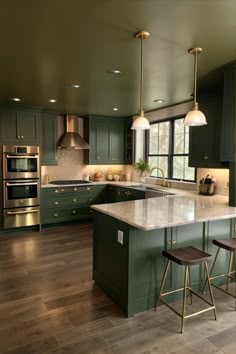 a large kitchen with green cabinets and marble counter tops, two stools in front of the island