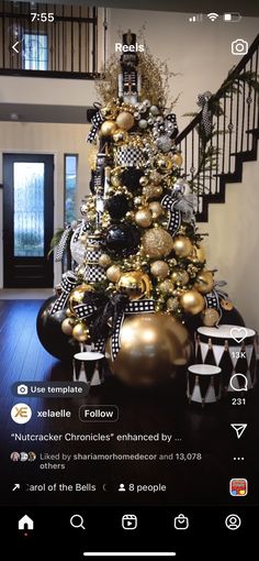 a christmas tree decorated with gold and black ornaments in a living room next to stairs