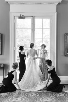 bridesmaids helping the bride get ready for her wedding at home in black and white