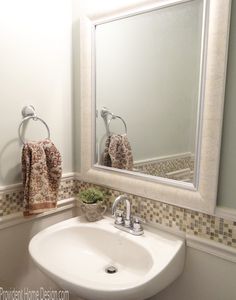 a white sink sitting under a bathroom mirror next to a wall mounted faucet