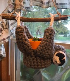 a stuffed slotty hanging from a tree branch with a potted plant in it