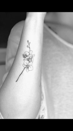 a black and white photo of a woman's arm with a flower tattoo on it