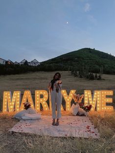 a woman standing in front of a marquee that says marry me