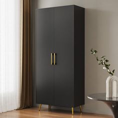 a black cabinet sitting next to a table with a vase on it and a window in the background