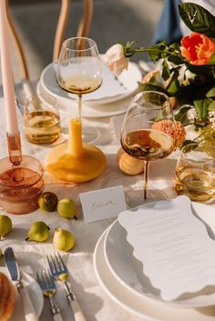 the table is set with wine glasses, plates and utensils