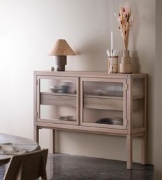 a sideboard with glass doors and drawers in a living room next to a lamp