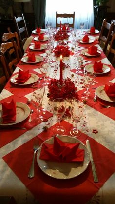 the table is set with red napkins and place settings for two people to sit at