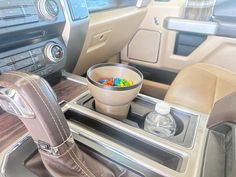 a cup filled with gummy bears sitting on top of a car dash board next to a steering wheel