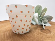 an orange patterned cup sitting on top of a wooden table next to a succulent plant