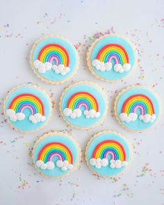 rainbow cookies with blue icing and sprinkles on a white tablecloth