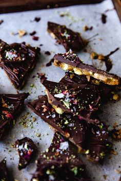 pieces of chocolate with sprinkles and nuts on a sheet of parchment paper