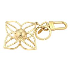 a gold keychain with a flower design on the front and center, attached to a