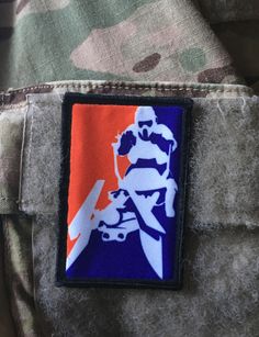 an orange and blue patch on the back of a soldier's uniform, depicting a motorcyclist