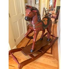 a wooden rocking horse sitting on top of a hard wood floor next to a door