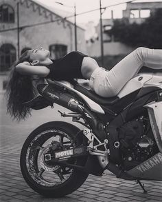 a beautiful woman laying on top of a motorcycle