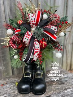 a pair of black rubber boots with red and white bows on them sitting in front of a wooden fence