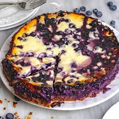 a blueberry cheesecake is cut into slices on a white plate with silverware