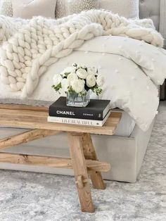 a bed with white flowers on top of it and a book sitting on the end table