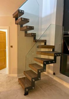 there is a glass stair case in the house with wood treads and metal handrails