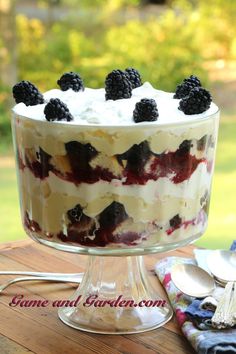 a cake with berries and whipped cream on top sitting on a table next to a fork