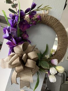 a wreath with purple flowers hanging on the side of a wall next to a door